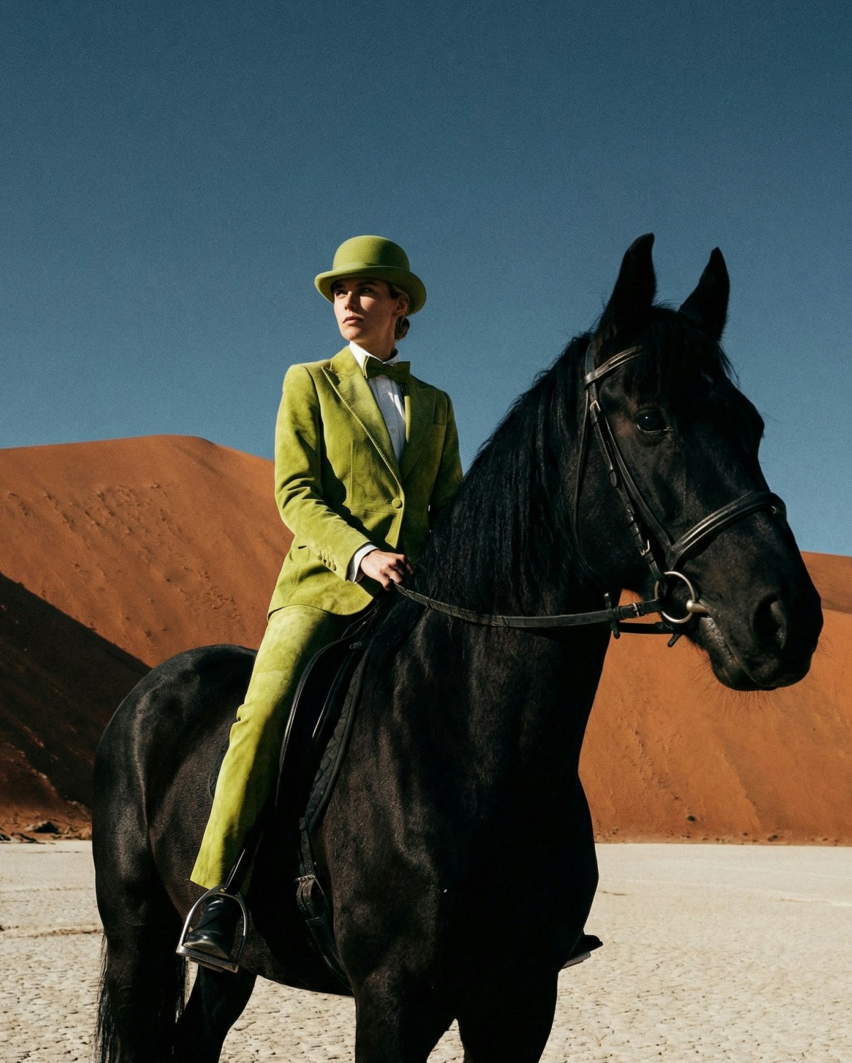 Surreal fashion editorial of a rider and a black horse in the desert